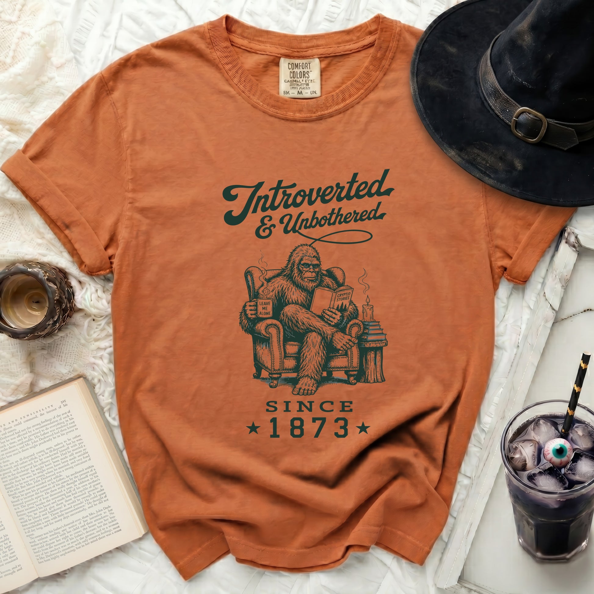 Orange Comfort Colors t-shirt features Bigfoot reading with text "Introverted & Unbothered Since 1873".