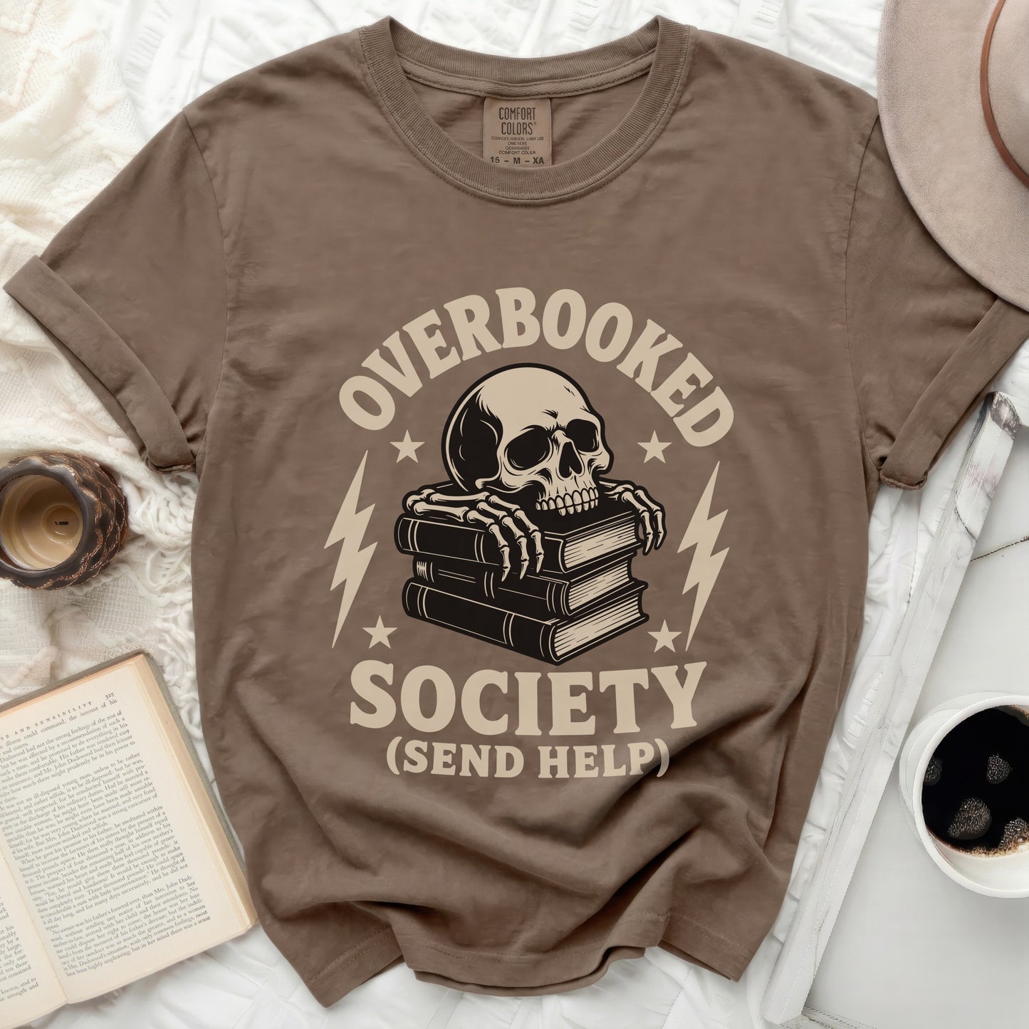 Brown t-shirt with a skeleton reading books and "Overbooked Society (Send Help)" graphic.