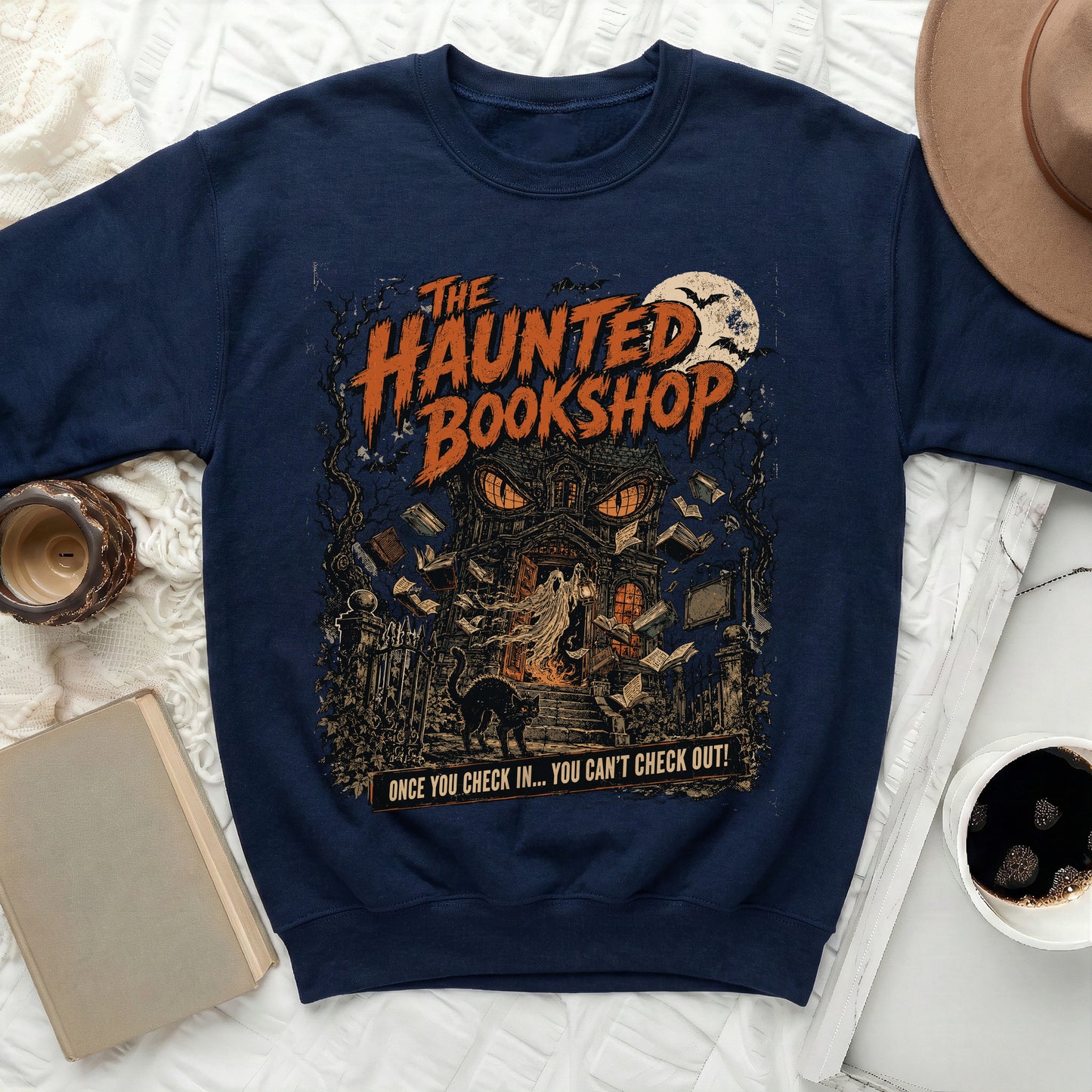 Navy sweatshirt with "The Haunted Bookshop" graphic featuring a spooky house, ghost, cat, and flying books.