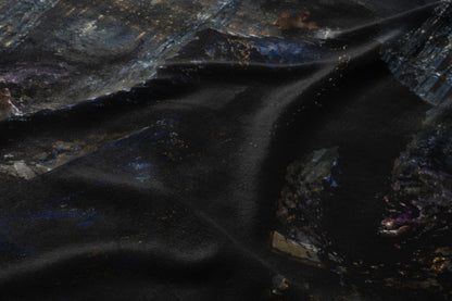 Dark fabric with an abstract, textured pattern of dark blues, grays, and gold.