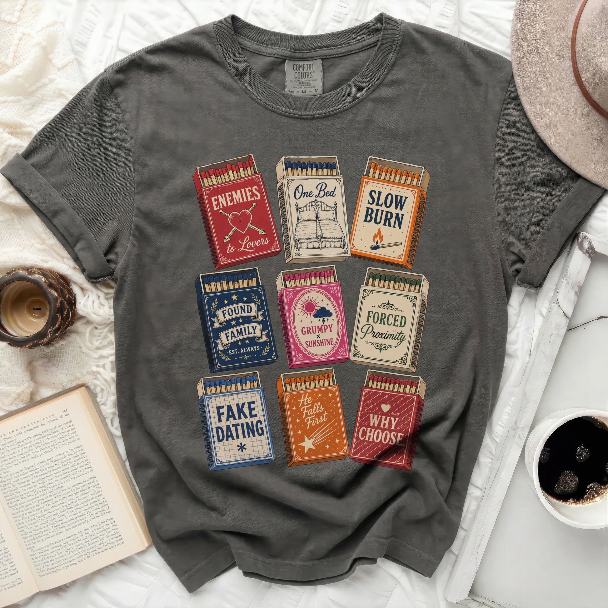 Dark grey t-shirt with matchbox designs: Enemies to Lovers, Slow Burn, Found Family, Grumpy Sunshine, Forced Proximity, Fake Dating, He Falls First, Why Choose.