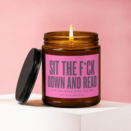 Amber candle with lit wick, black lid off, reads "SIT THE F*CK DOWN AND READ"