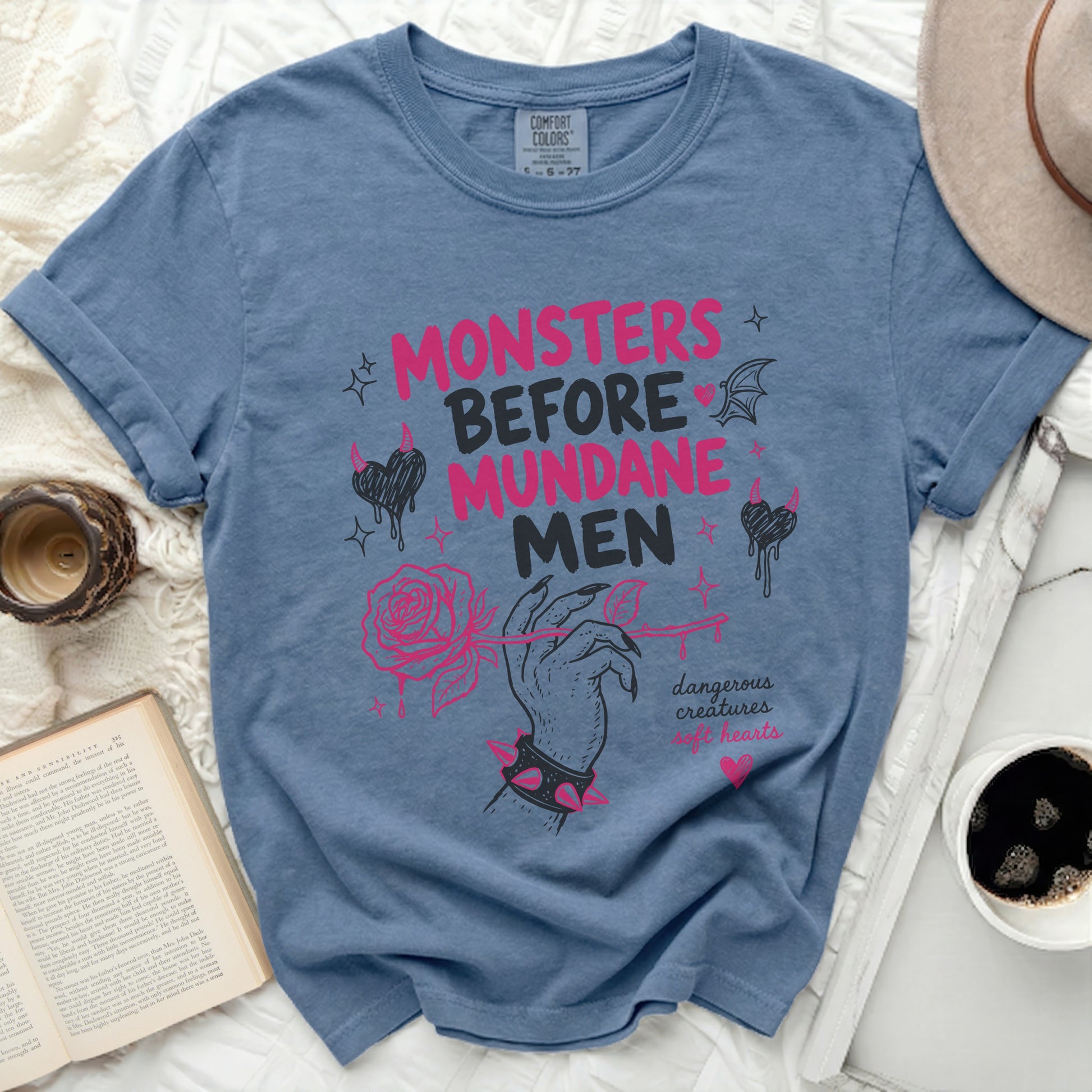 Blue t-shirt with pink text and graphics: "Monsters Before Mundane Men"