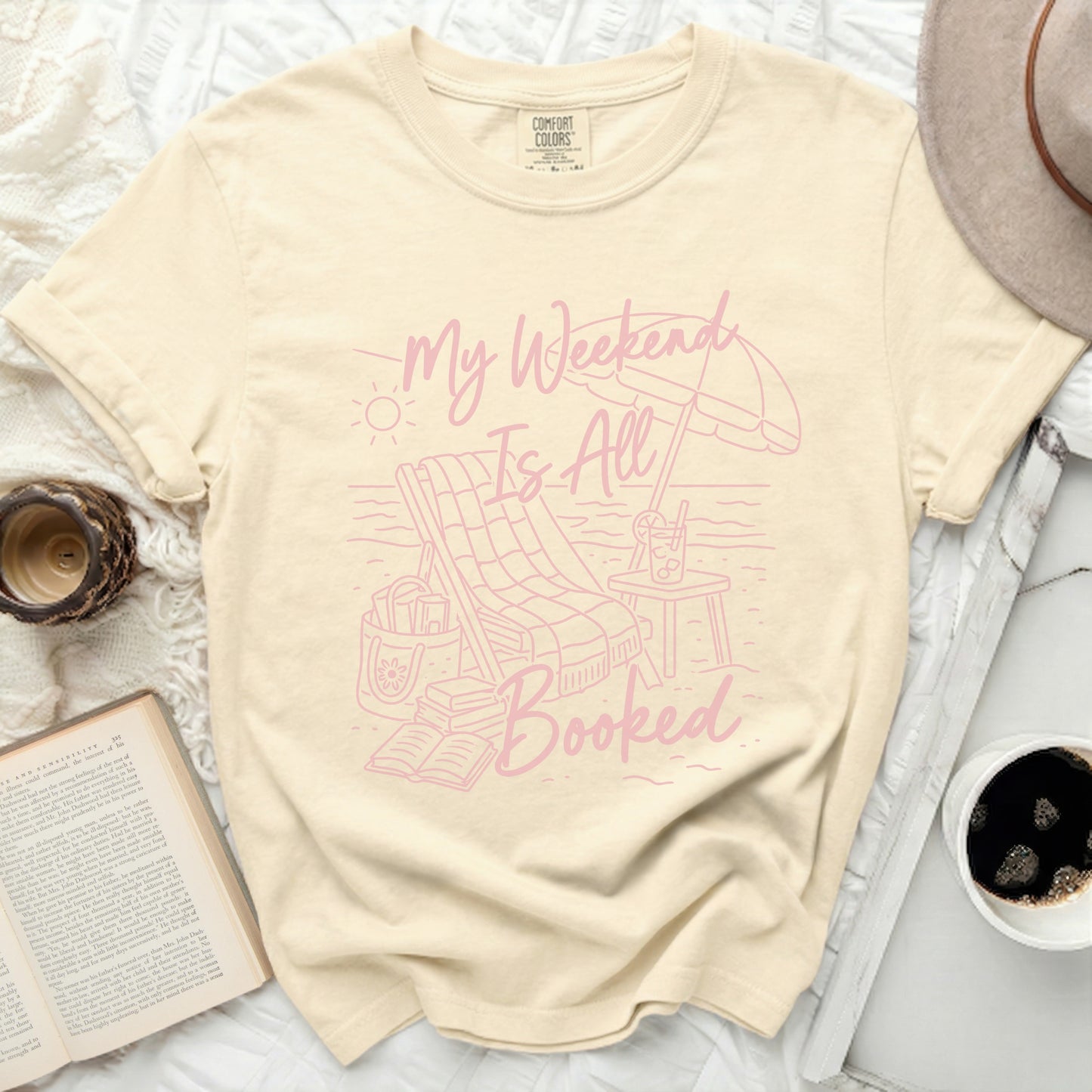 Cream t-shirt with "My Weekend Is All Booked" beach graphic.