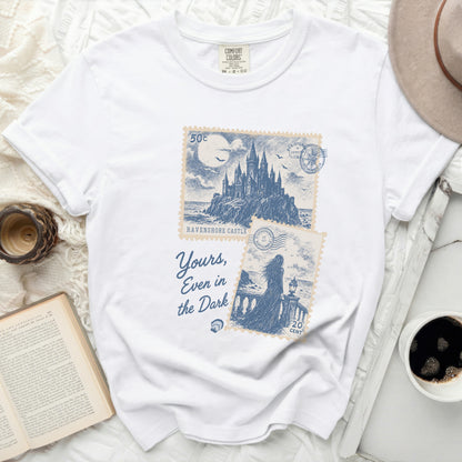 White t-shirt with "Yours, Even in the Dark" and castle stamps.