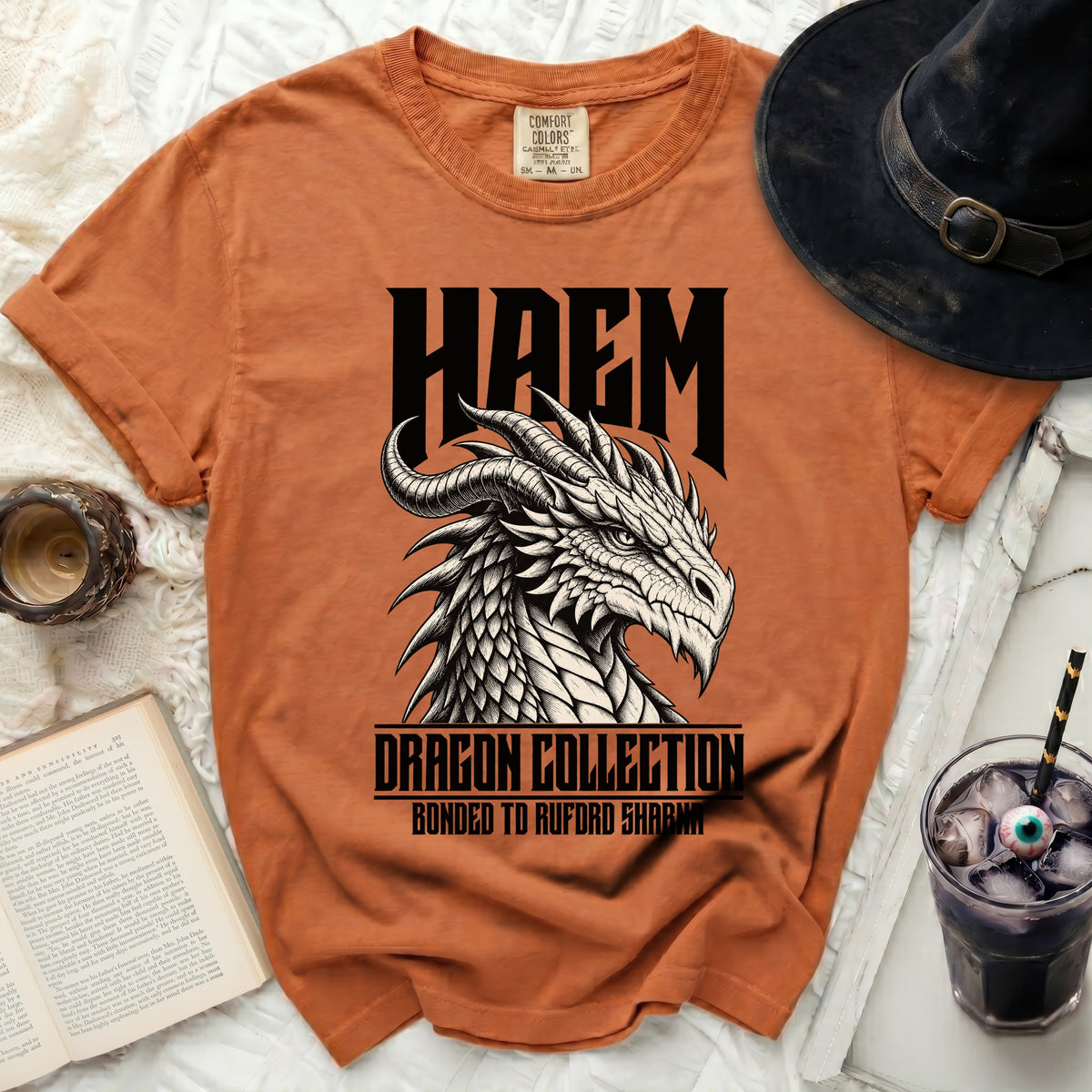 Orange t-shirt with black HAEM logo, dragon illustration, and text.