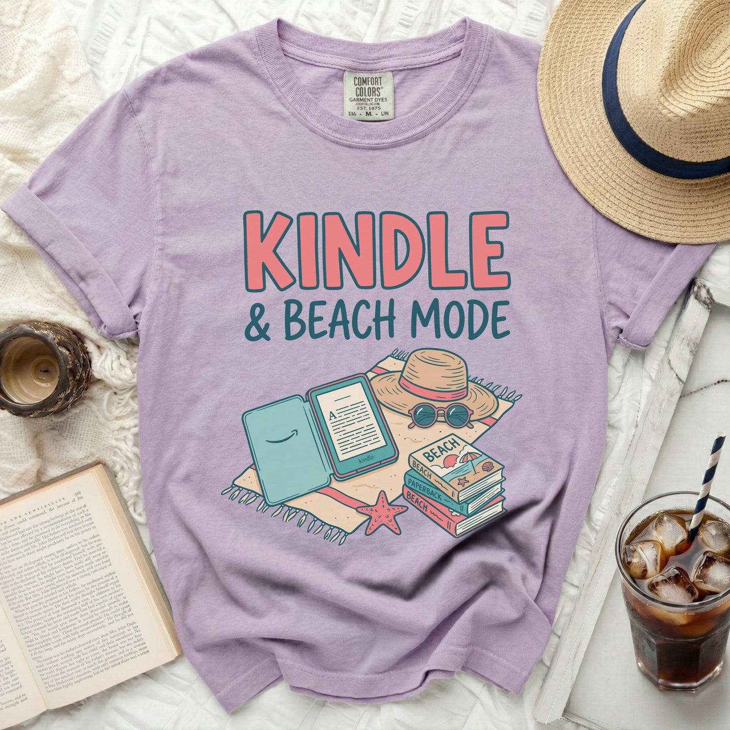 Purple t-shirt with "KINDLE & BEACH MODE" text, book, and beach hat.