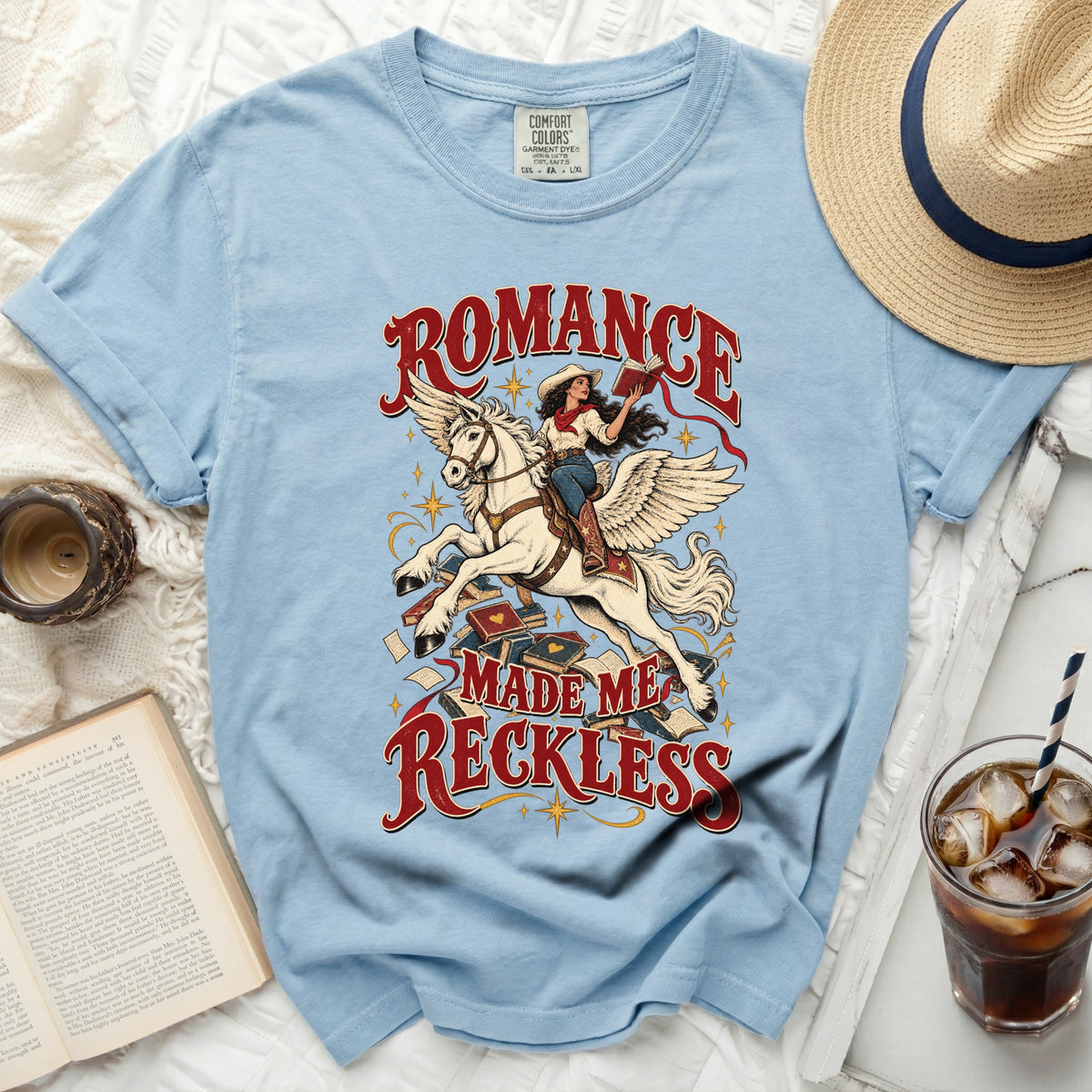 Light blue t-shirt with "Romance Made Me Reckless" graphic of a woman on a winged horse.