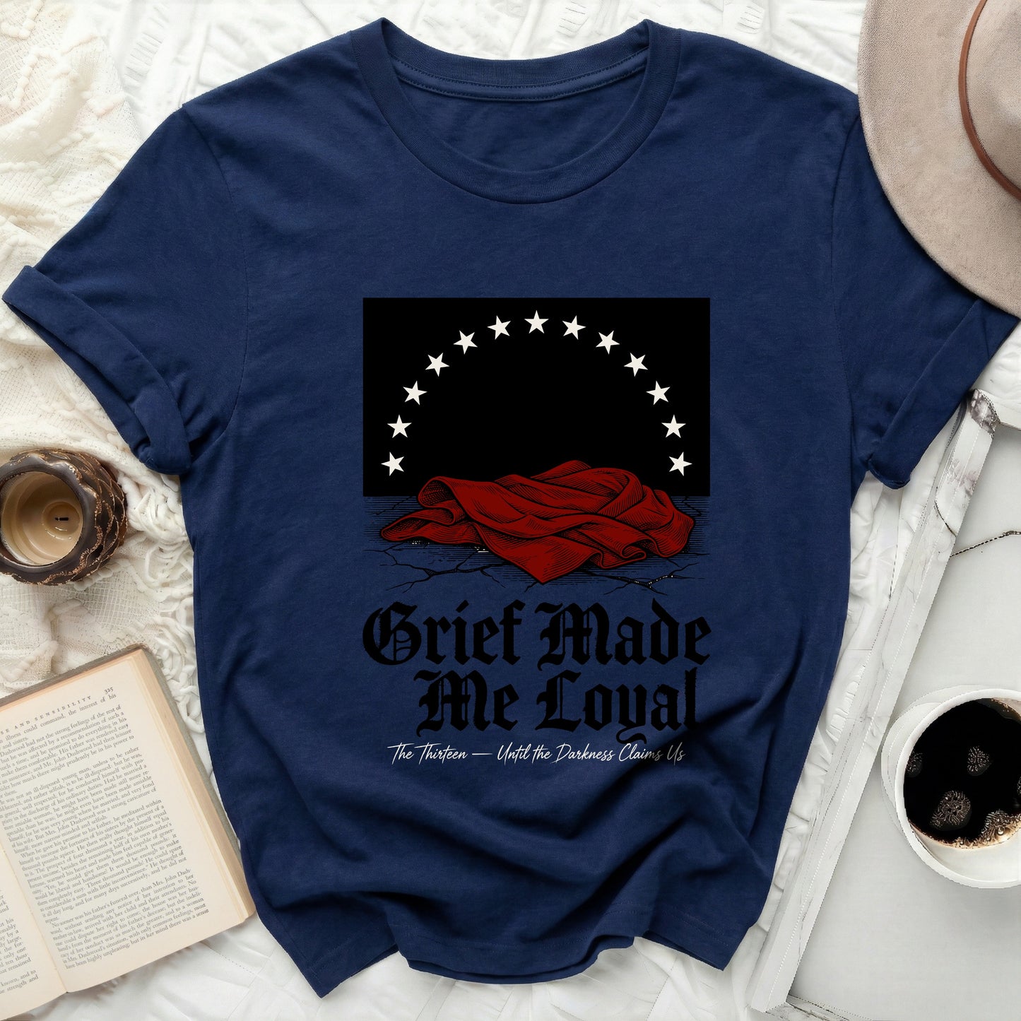 Navy t-shirt with "Grief Made Me Loyal" and "The Thirteen" text.
