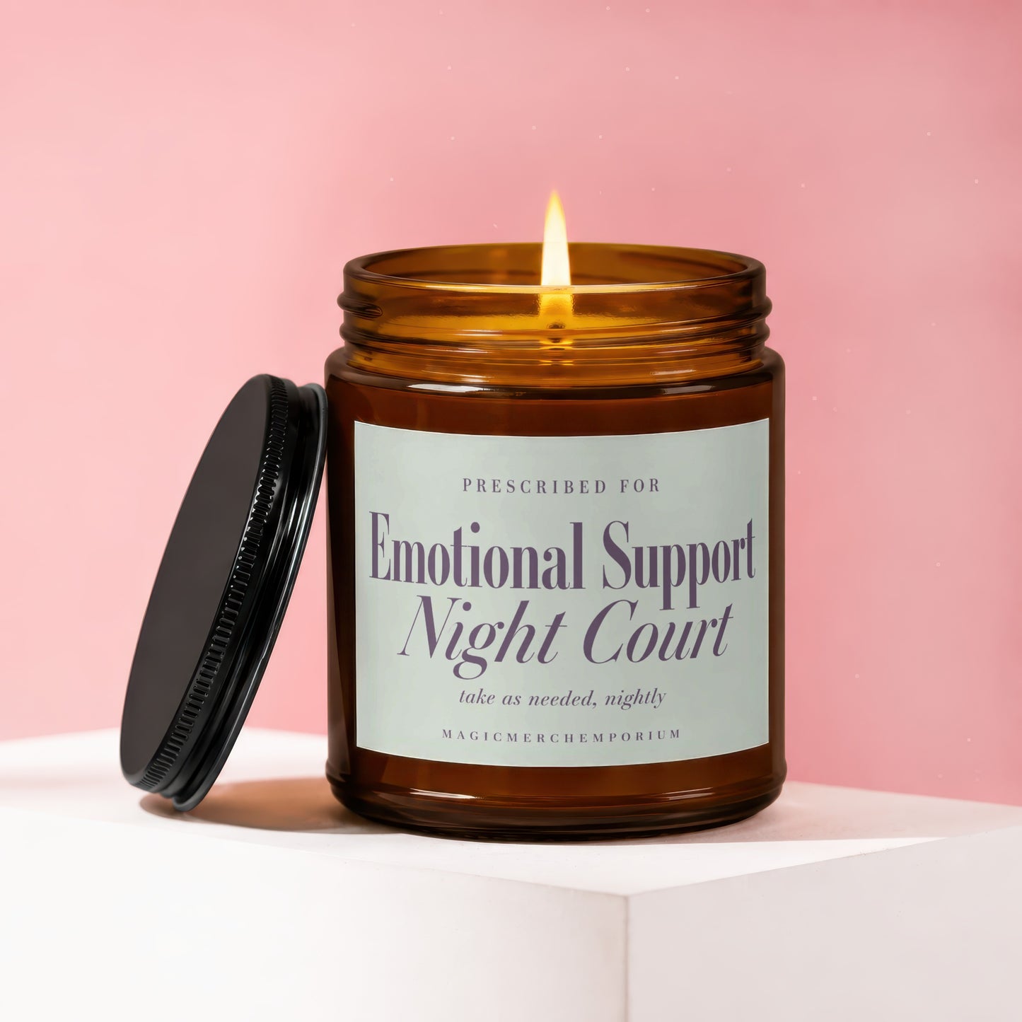 Amber jar candle with lit wick and black lid, reads "Emotional Support Night Court".