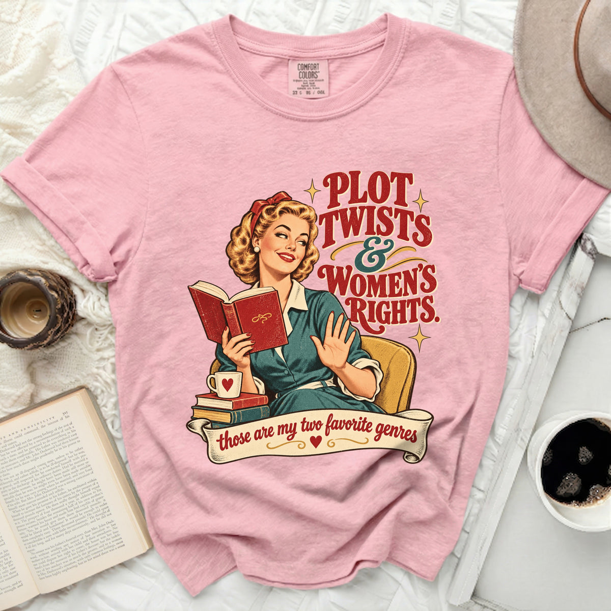 Pink t-shirt with graphic of woman reading and text "Plot Twists & Women's Rights."