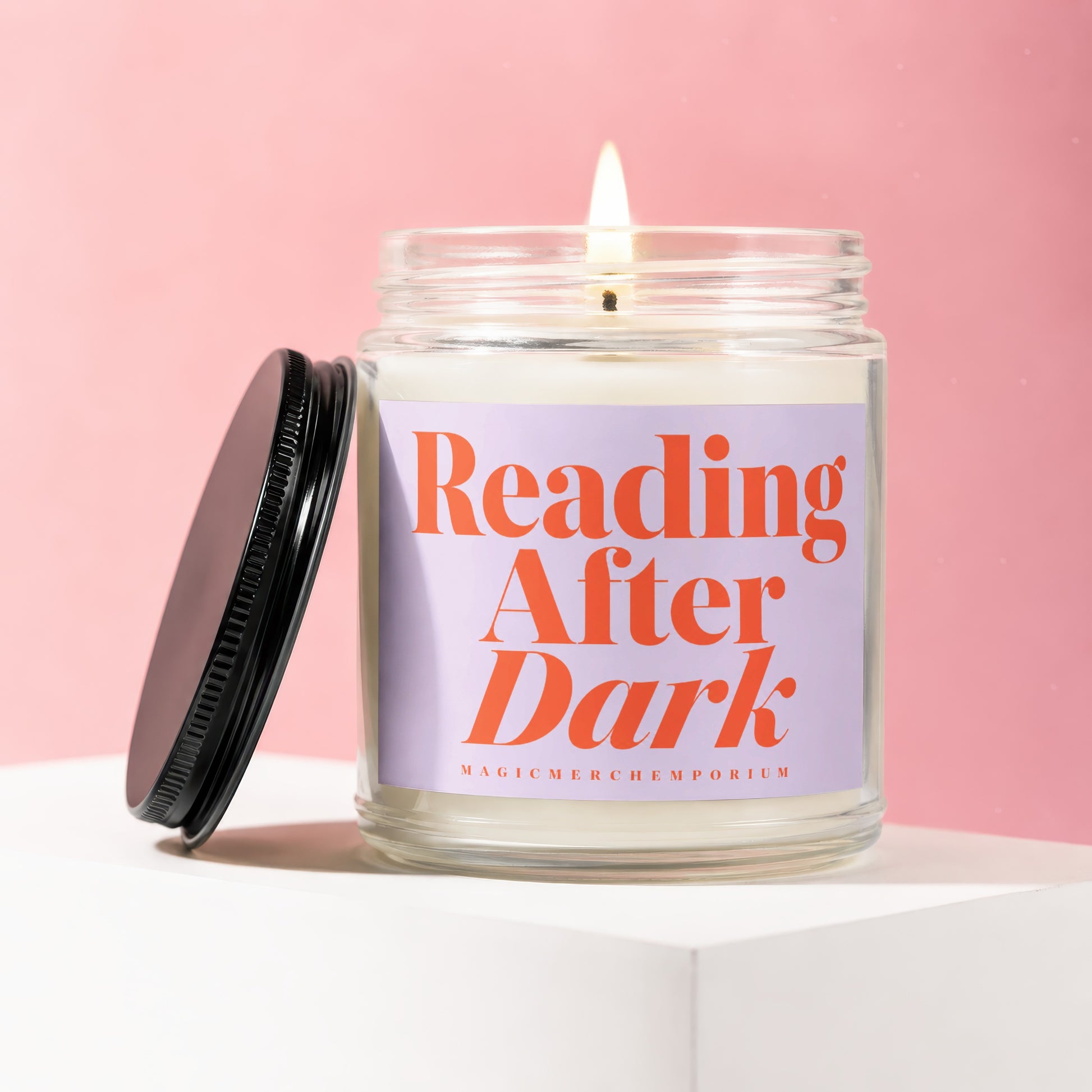 Glass jar candle with lit wick, "Reading After Dark" text on purple label.