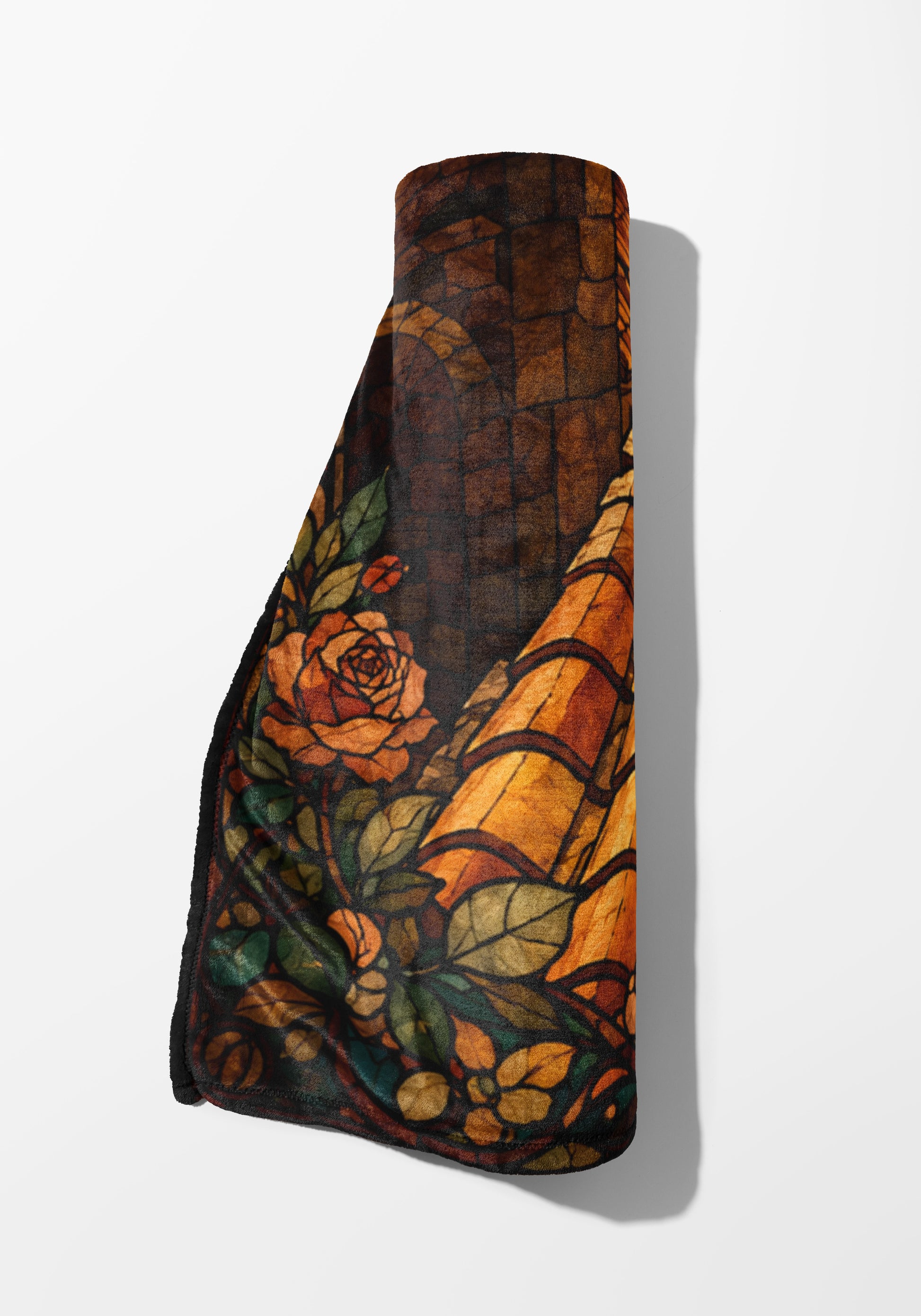 Rolled blanket with stained glass rose and leaf design in warm tones.