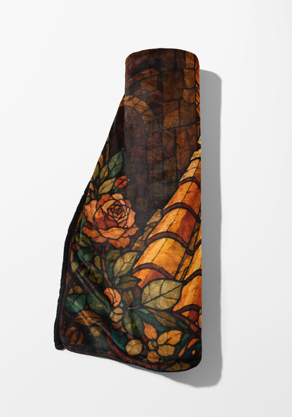 Rolled blanket with stained glass rose and leaf design in warm tones.