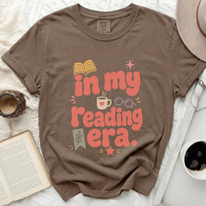 Brown t-shirt with "in my reading era." text and book graphics.