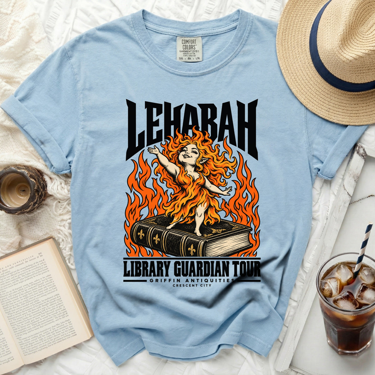 Light blue t-shirt graphic: fire-haired figure on book, "LEHABAH LIBRARY GUARDIAN TOUR" text.