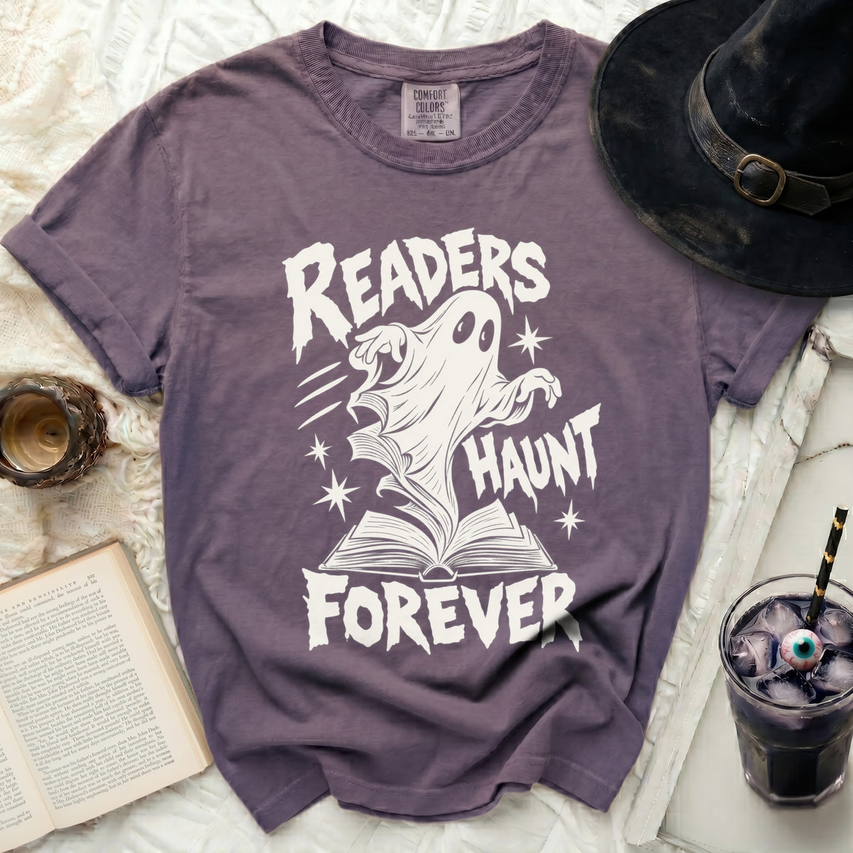 Purple t-shirt with white ghost reading a book and text "READERS HAUNT FOREVER".
