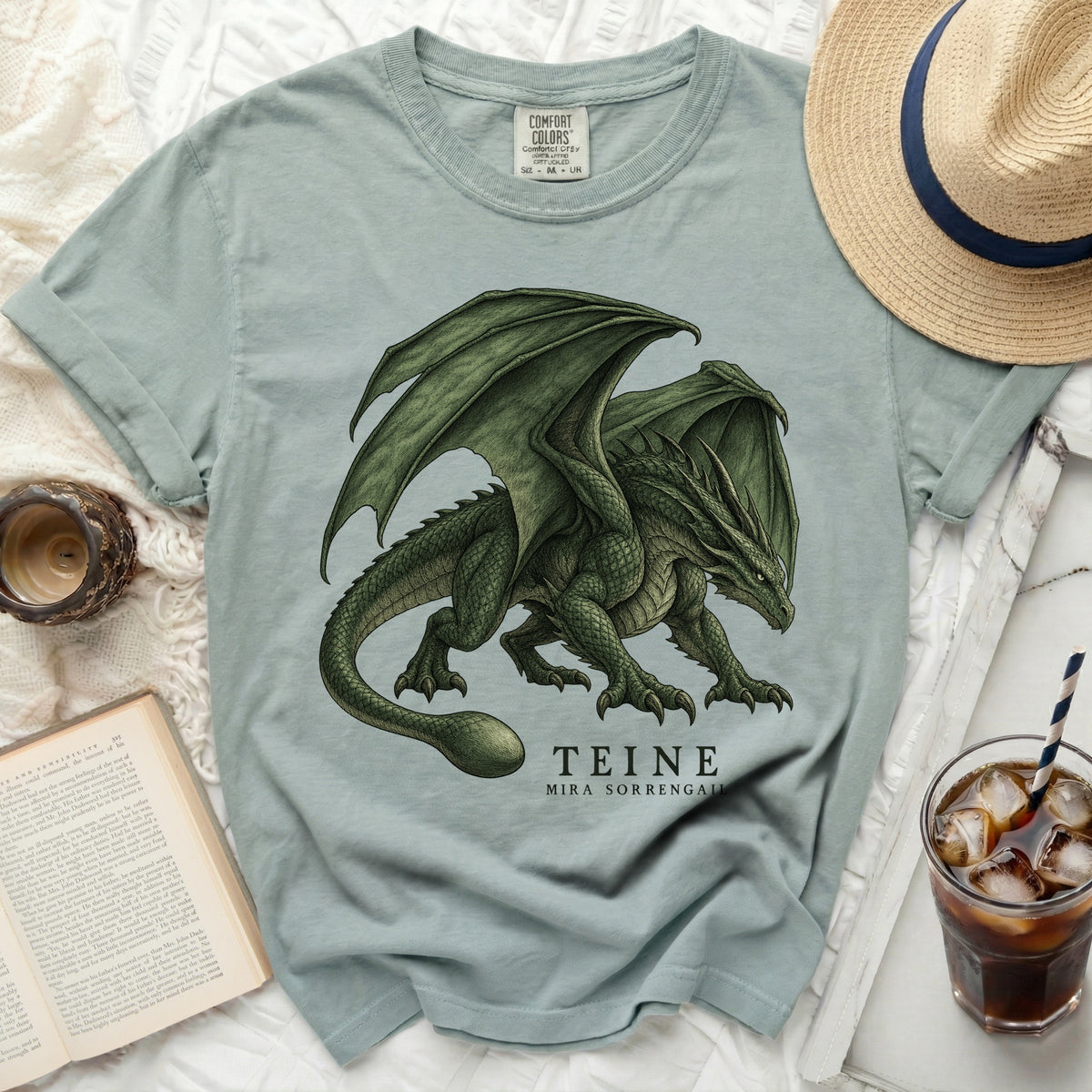 Light blue t-shirt with a green dragon graphic and "TEINE MIRA SORRENGALI" text.