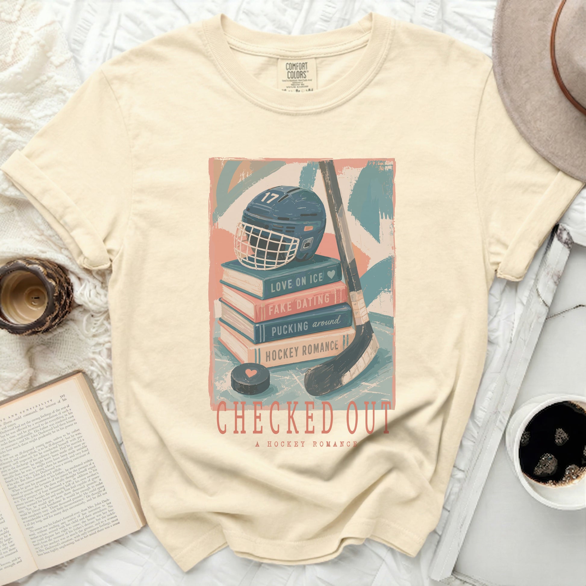 Cream t-shirt with stacked books, hockey helmet, and stick, featuring text.