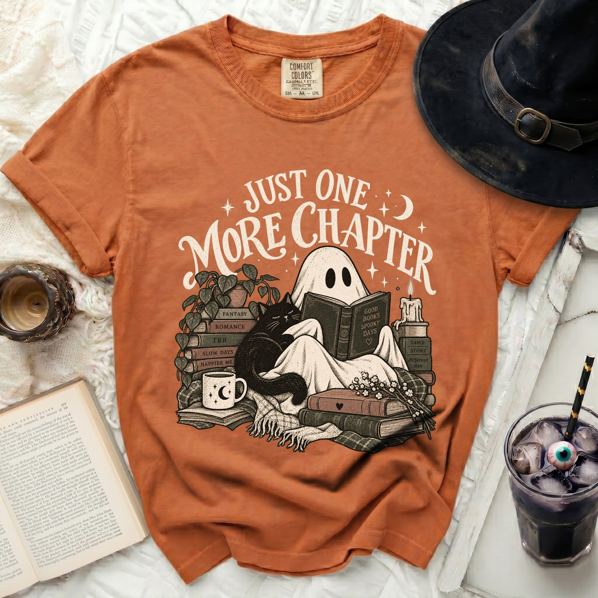 Orange t-shirt with ghost, cat, books, and "Just One More Chapter" text.