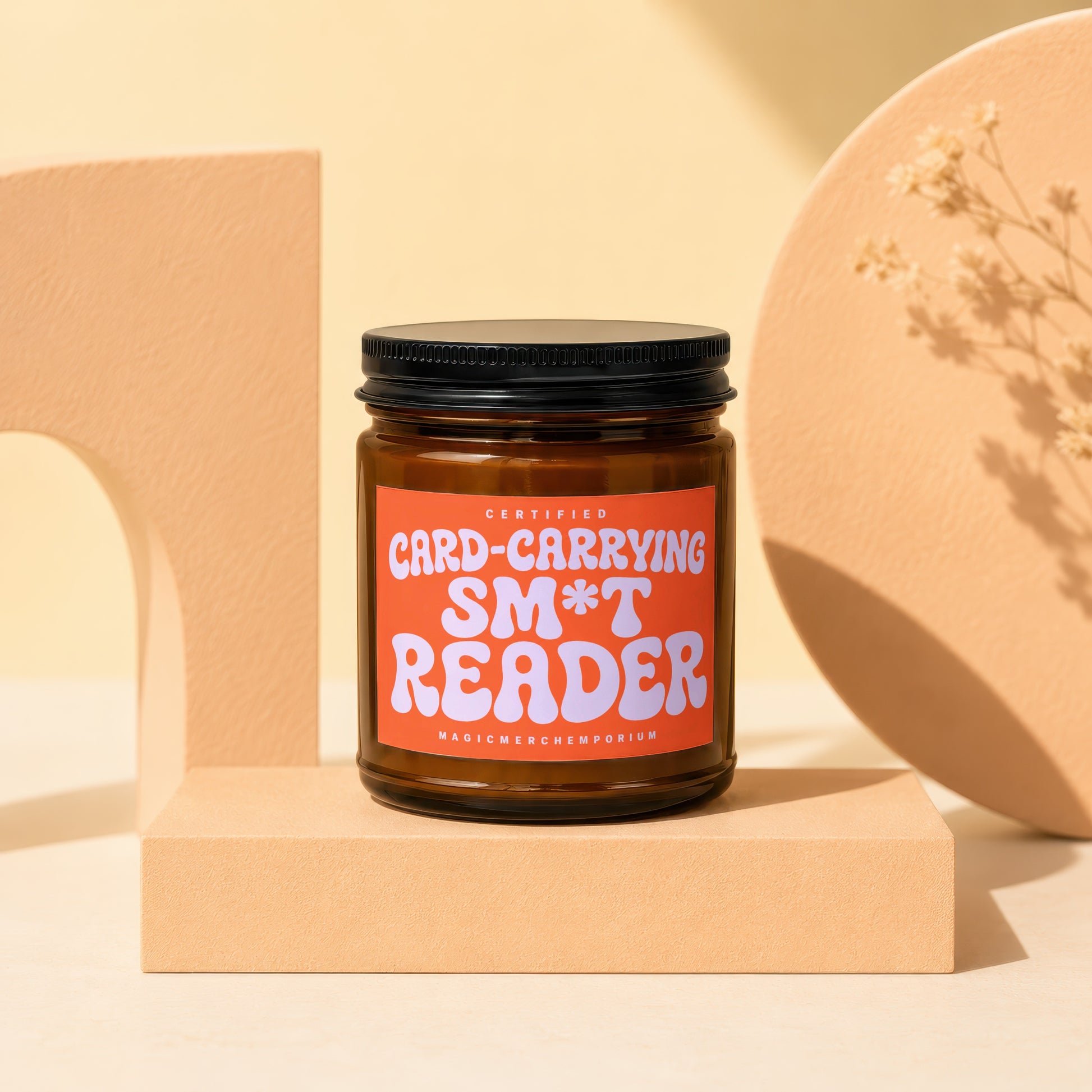 Amber jar candle with orange label reading "Certified Card-Carrying Sm*t Reader".