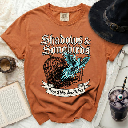 Orange t-shirt with "Shadows & Songbirds" and bird design.