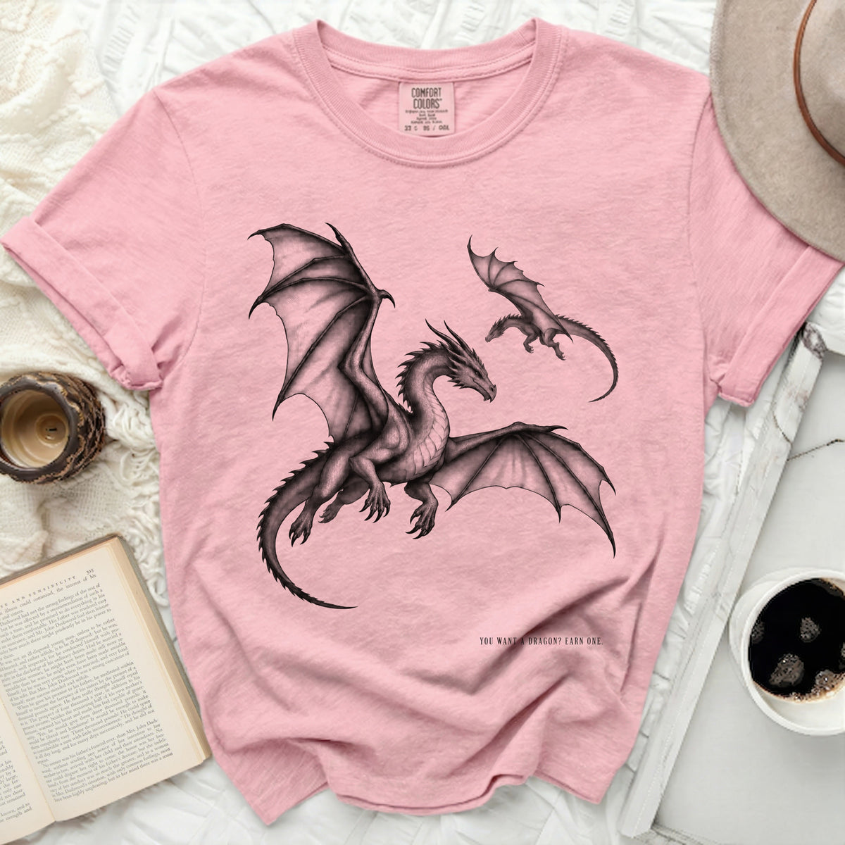 Pink t-shirt with graphic of a large and small dragon, and text "YOU WANT A DRAGON? EARN ONE."