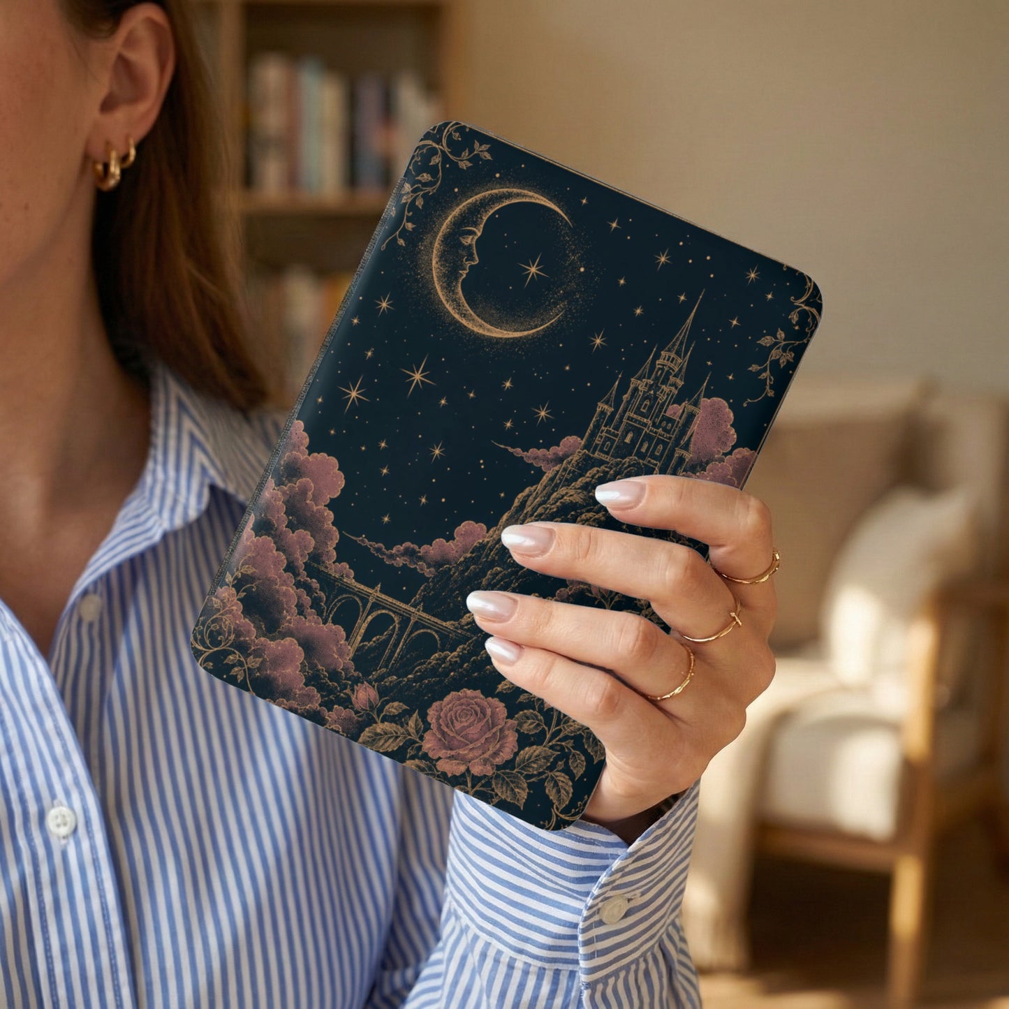 Celestial castle and moon design on a dark notebook held by a woman.