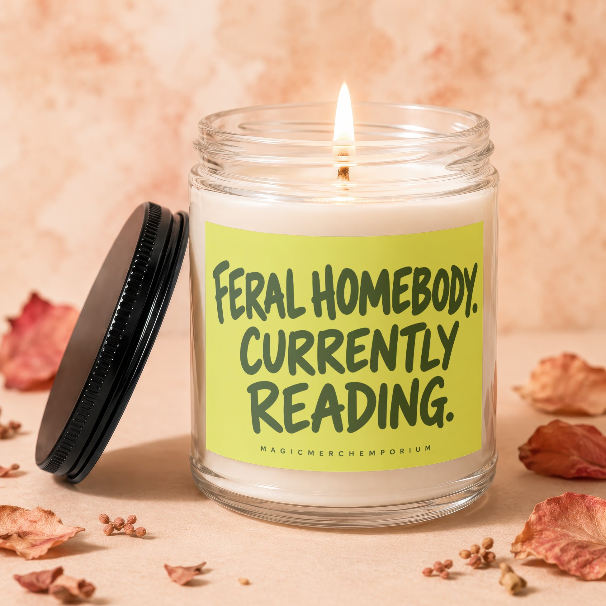 Feral Homebody Currently Reading candle, lit flame, black lid beside jar.