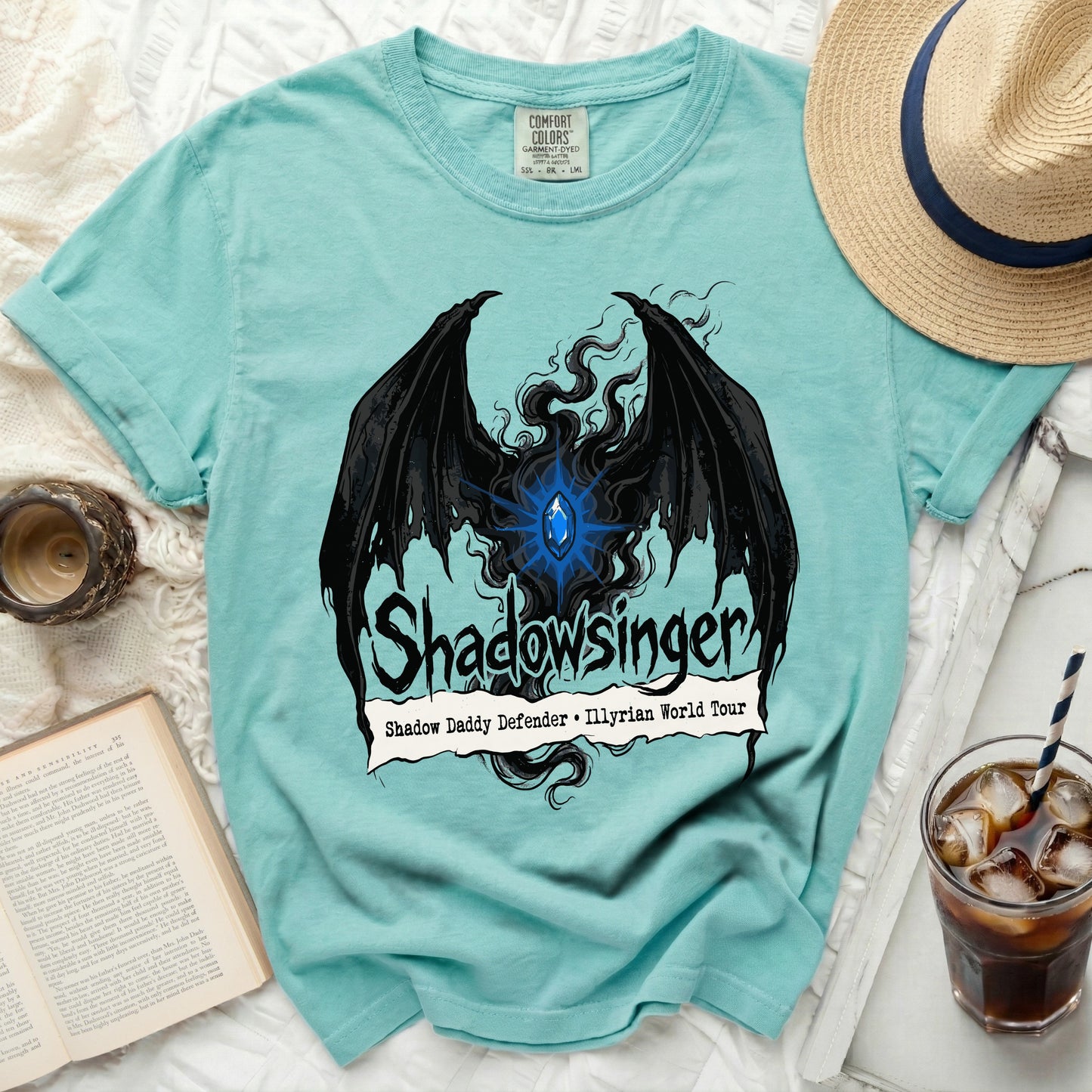 Teal t-shirt with black dragon wings, blue gem, and "Shadowsinger" text.