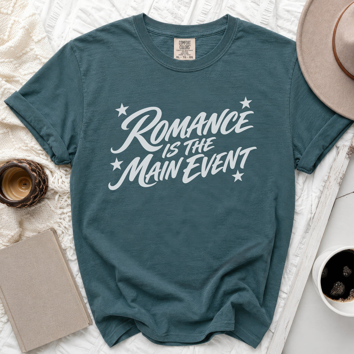 Teal t-shirt with white text "Romance Is The Main Event" and stars.