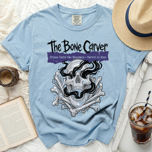 Light blue t-shirt with "The Bone Carver" and skull graphic.