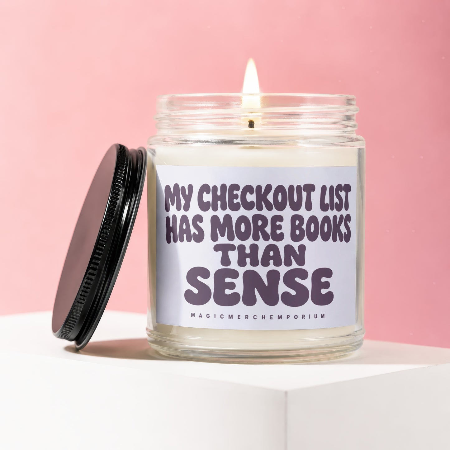 Candle with text "MY CHECKOUT LIST HAS MORE BOOKS THAN SENSE".