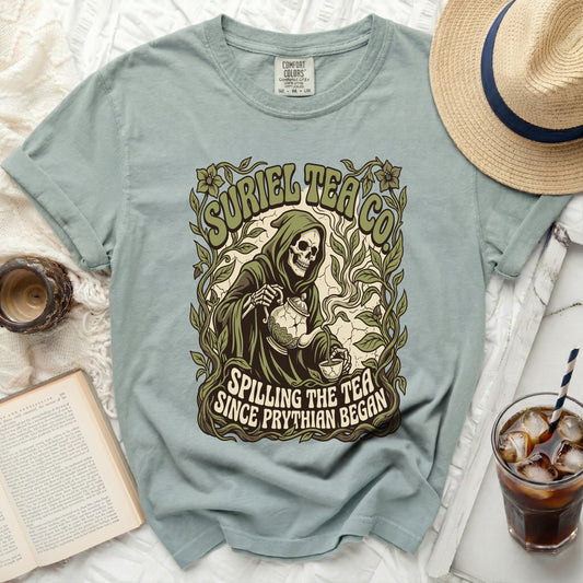 Pale blue t-shirt with grim reaper pouring tea; "SURIEL TEA CO." and "SPILLING THE TEA SINCE PRYTHIAN BEGAN".
