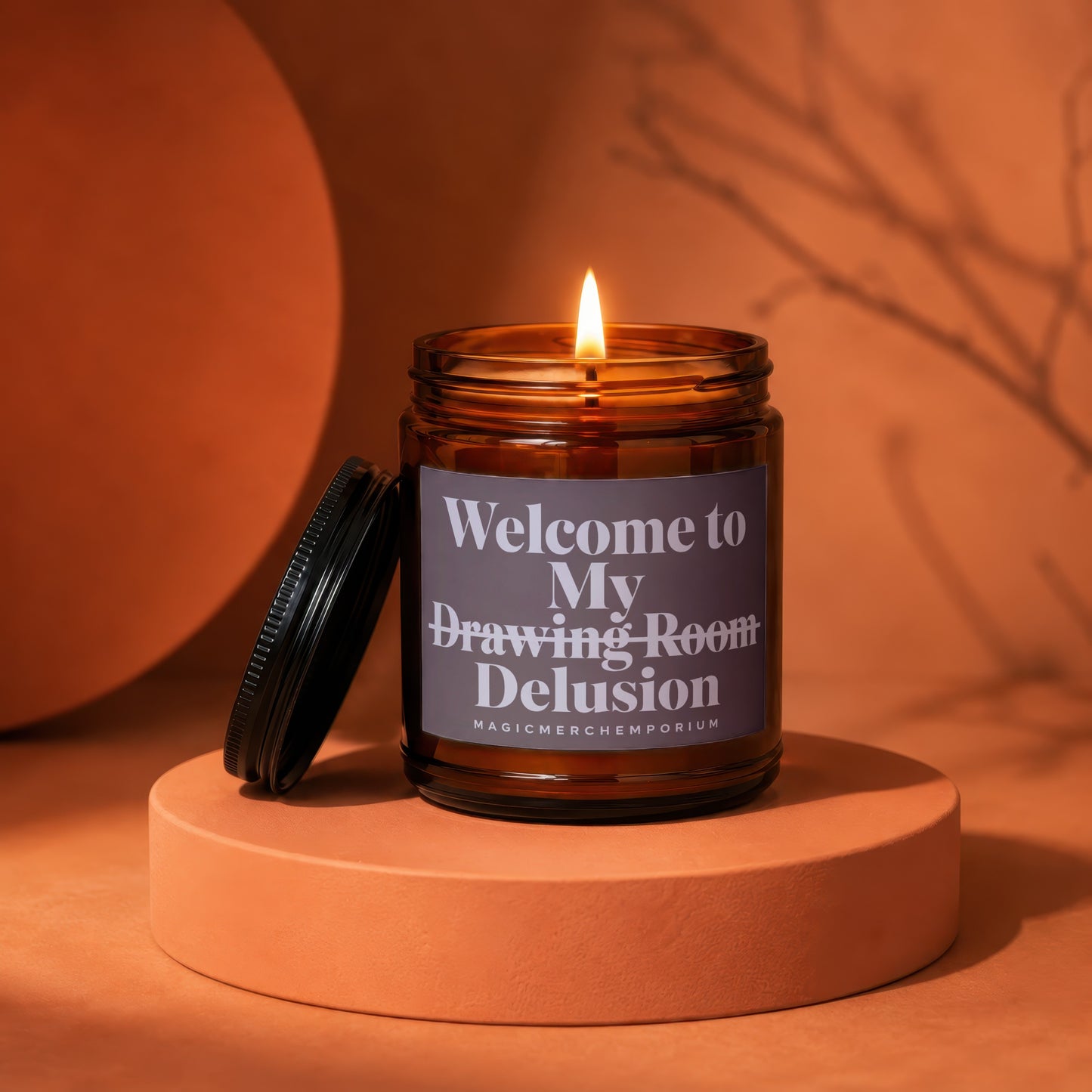 Amber jar candle with lit flame, "Welcome to My Drawing Room Delusion" text.