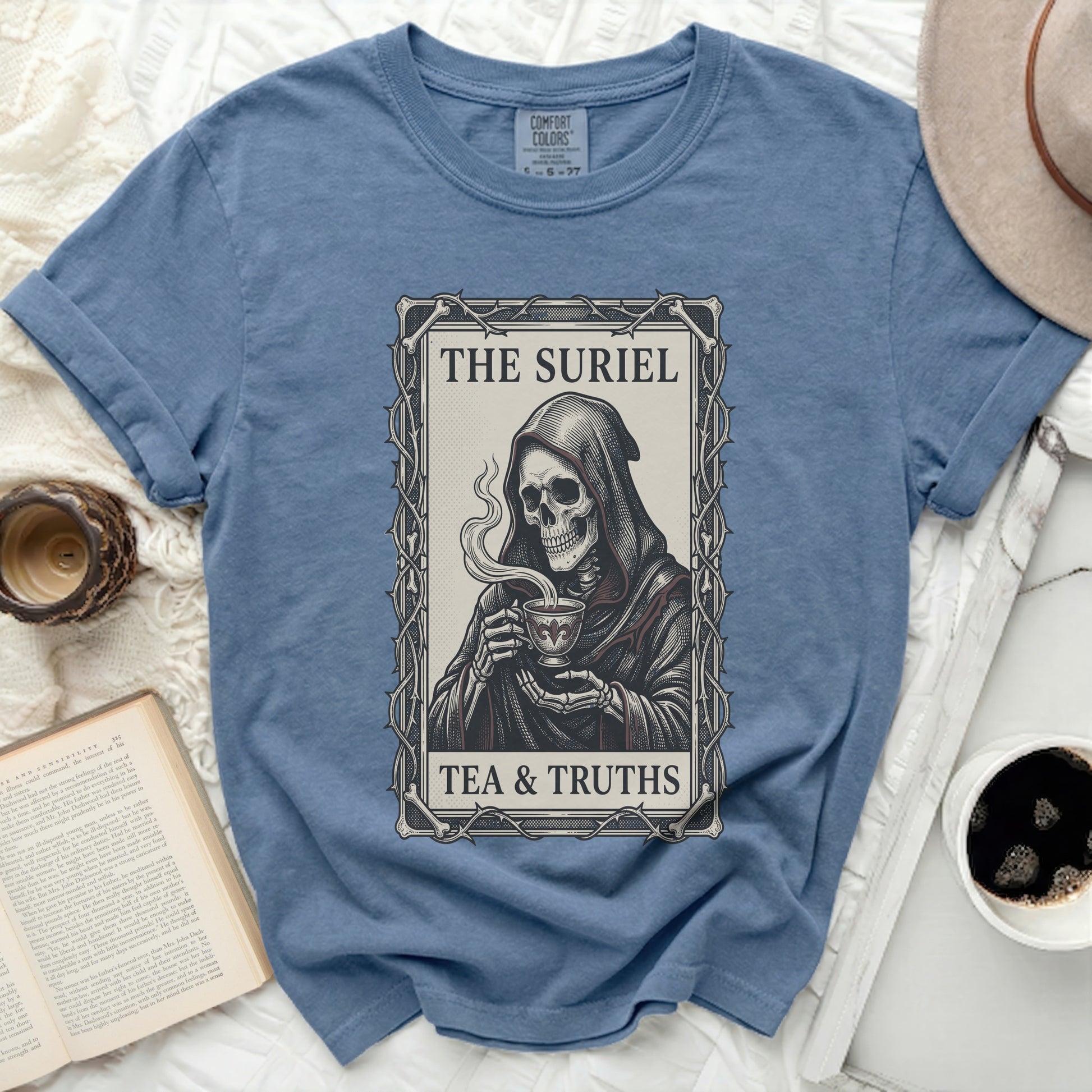 Blue t-shirt with graphic of Grim Reaper holding tea cup, text "THE SURIEL TEA & TRUTHS".