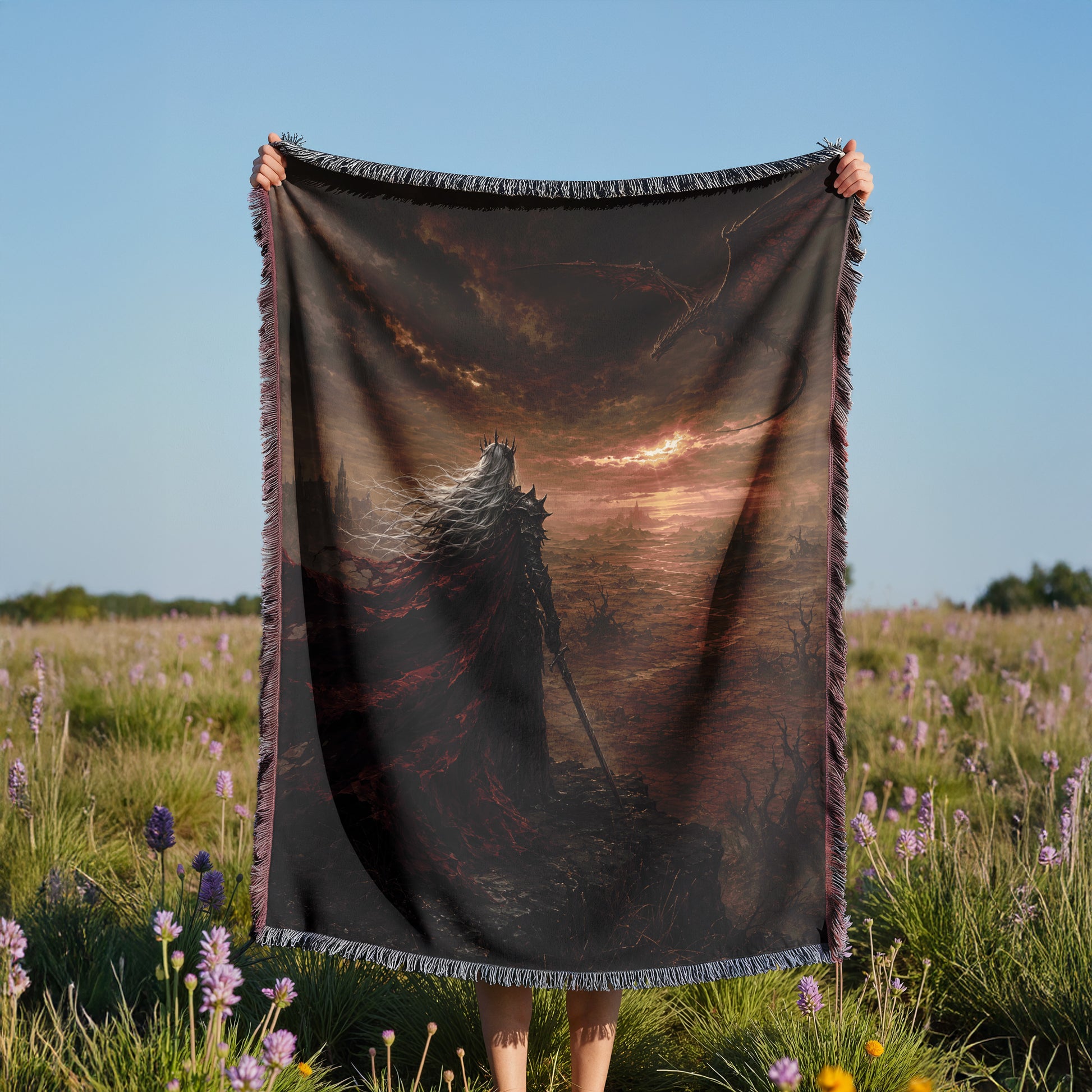 A person is holding a large black blanket with a painting of a dark, ominous figure on it, standing in a field of purple flowers.