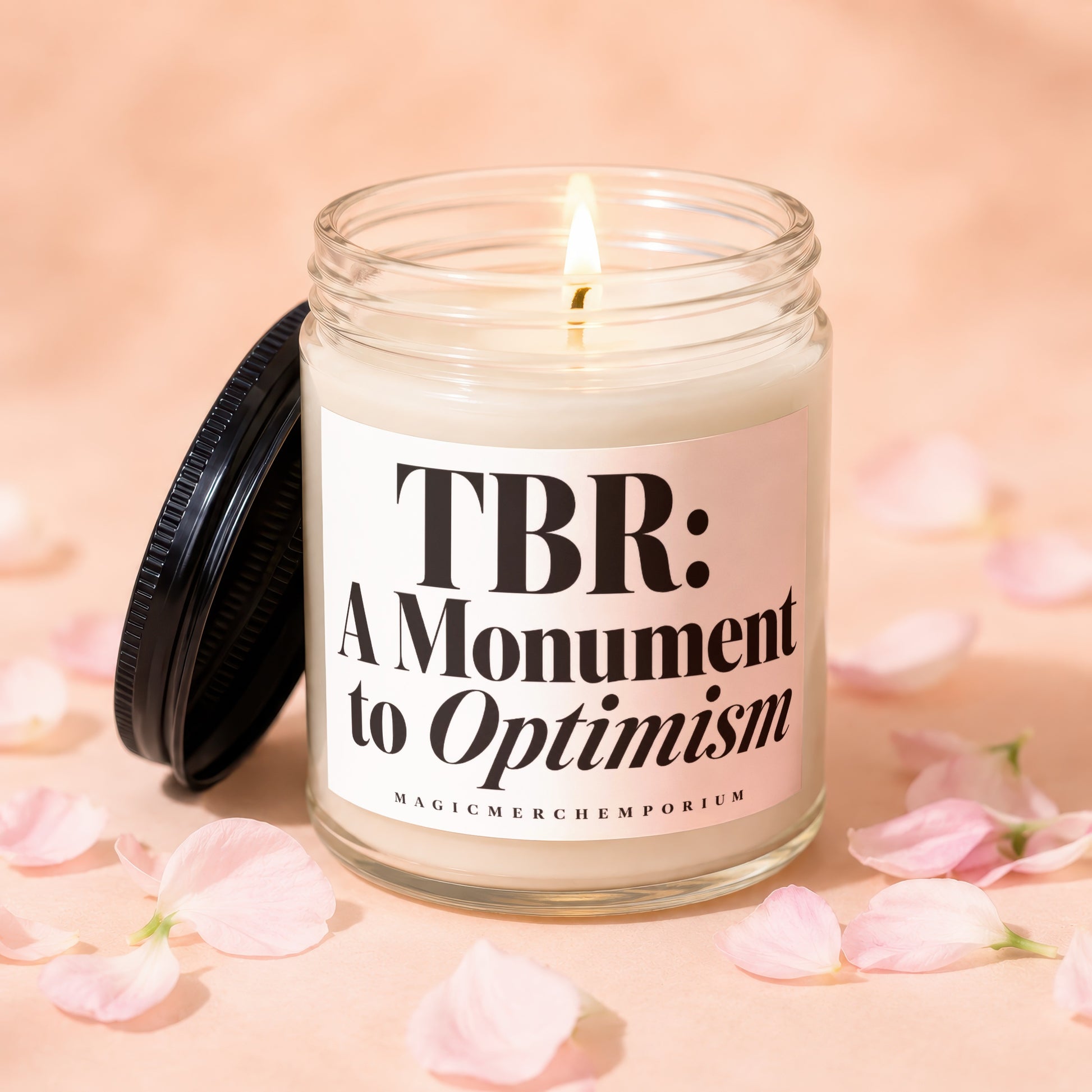 Glass candle lit with flame, reads "TBR: A Monument to Optimism."