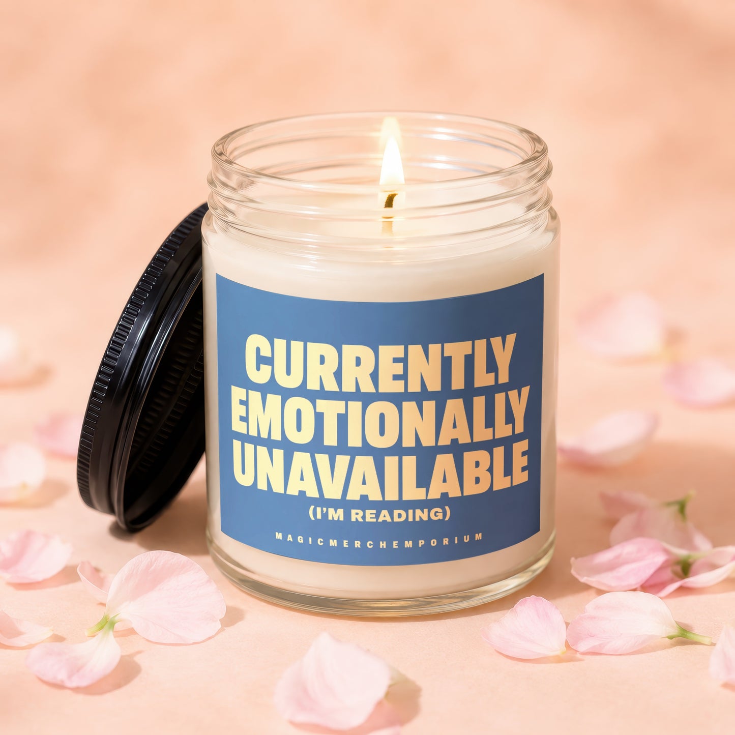 Glass jar candle with lit wick and blue label reading "Currently Emotionally Unavailable (I'm Reading)".