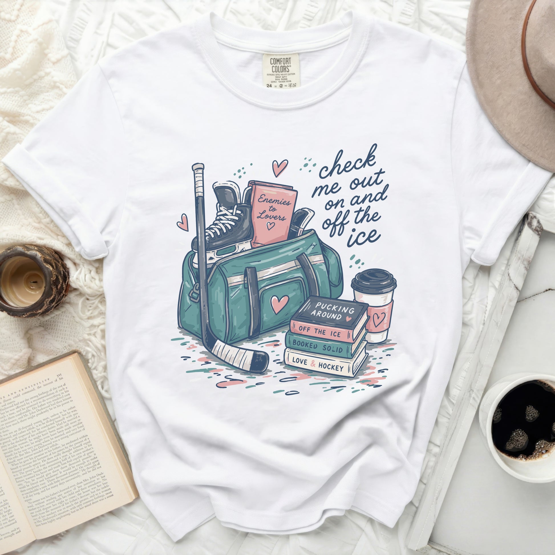 White t-shirt with "Enemies to Lovers" graphic featuring hockey gear and books.