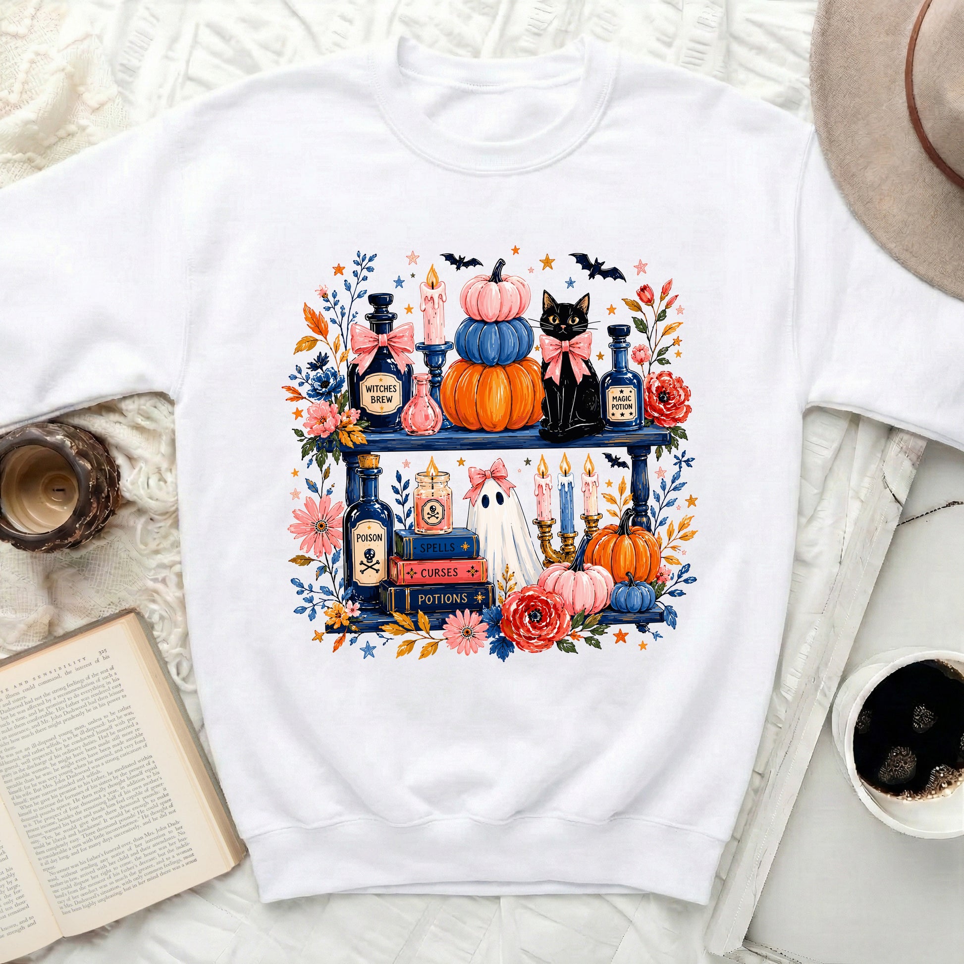 White crewneck sweatshirt with a watercolor Halloween shelf graphic including a black cat, pumpkins, and potions.