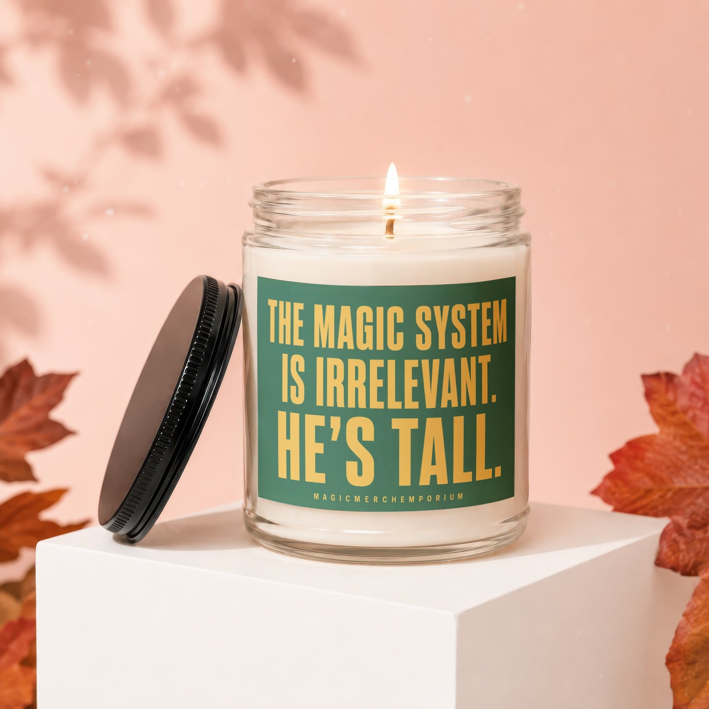 Glass candle with green label reading "The Magic System is Irrelevant. He's Tall."