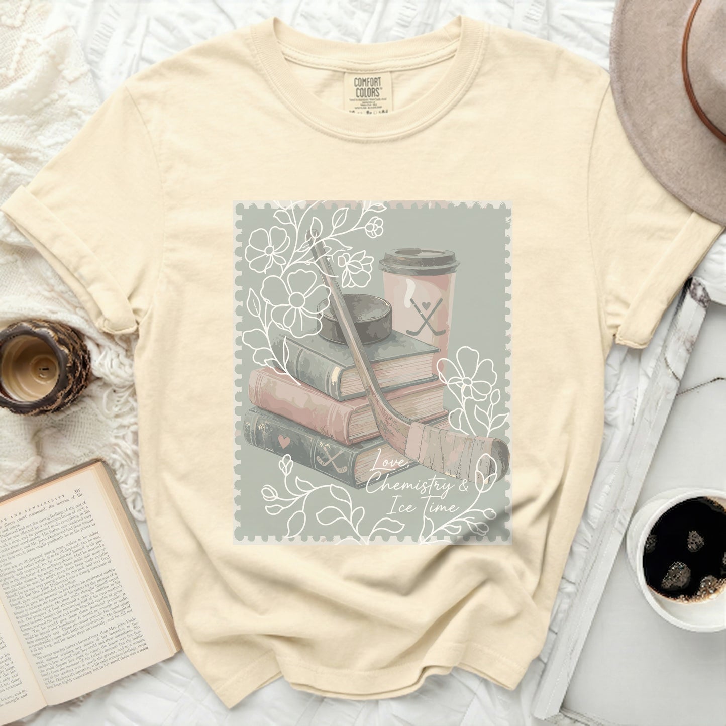 Cream t-shirt with postage stamp graphic: books, hockey stick, skates, cup, and text.