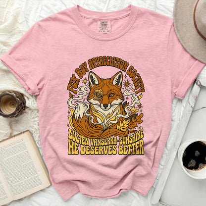 Pink t-shirt with a fox wearing a monocle and text "FOX BOY APPRECIATION SOCIETY LUCIEN VANSERRA SUNSHINE HE DESERVES BETTER".