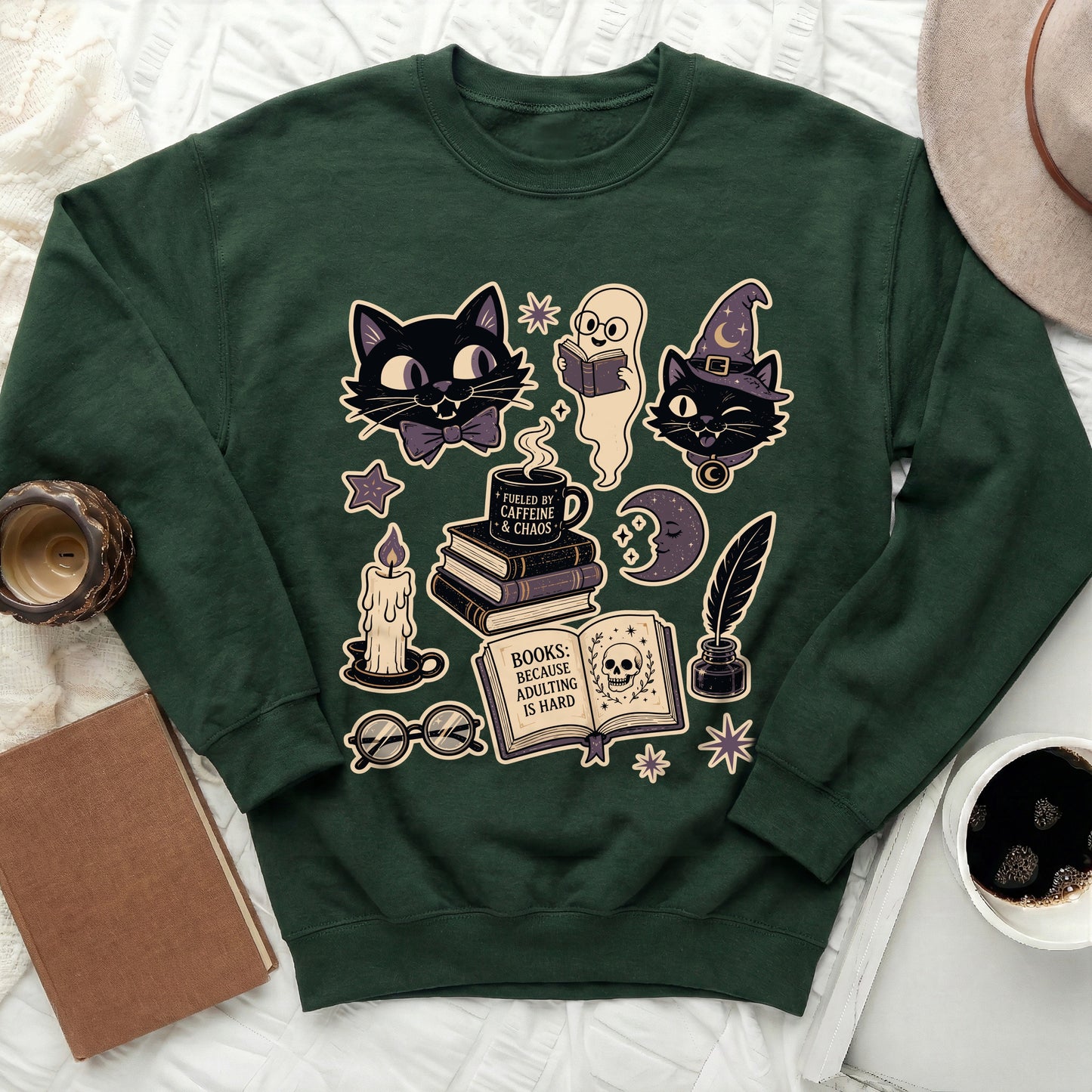 Green sweatshirt with spooky cute Halloween-themed graphics, including cats, ghosts, books, and coffee.