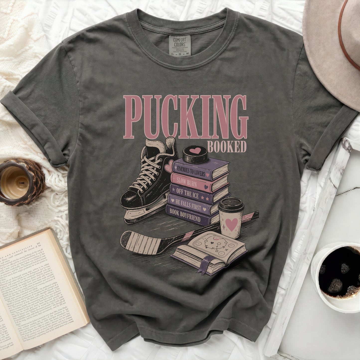T-shirt with ice skates, hockey stick, and stacked books with "Pucking Booked" text.