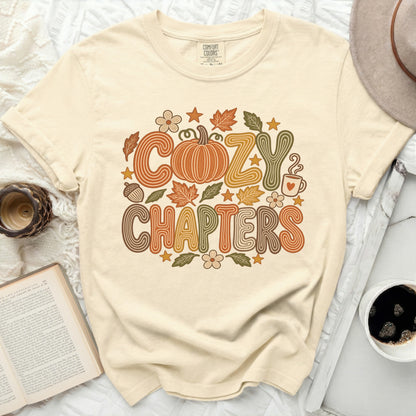 Cream t-shirt with "Cozy Chapters" text, pumpkin, leaves, and coffee cup design.