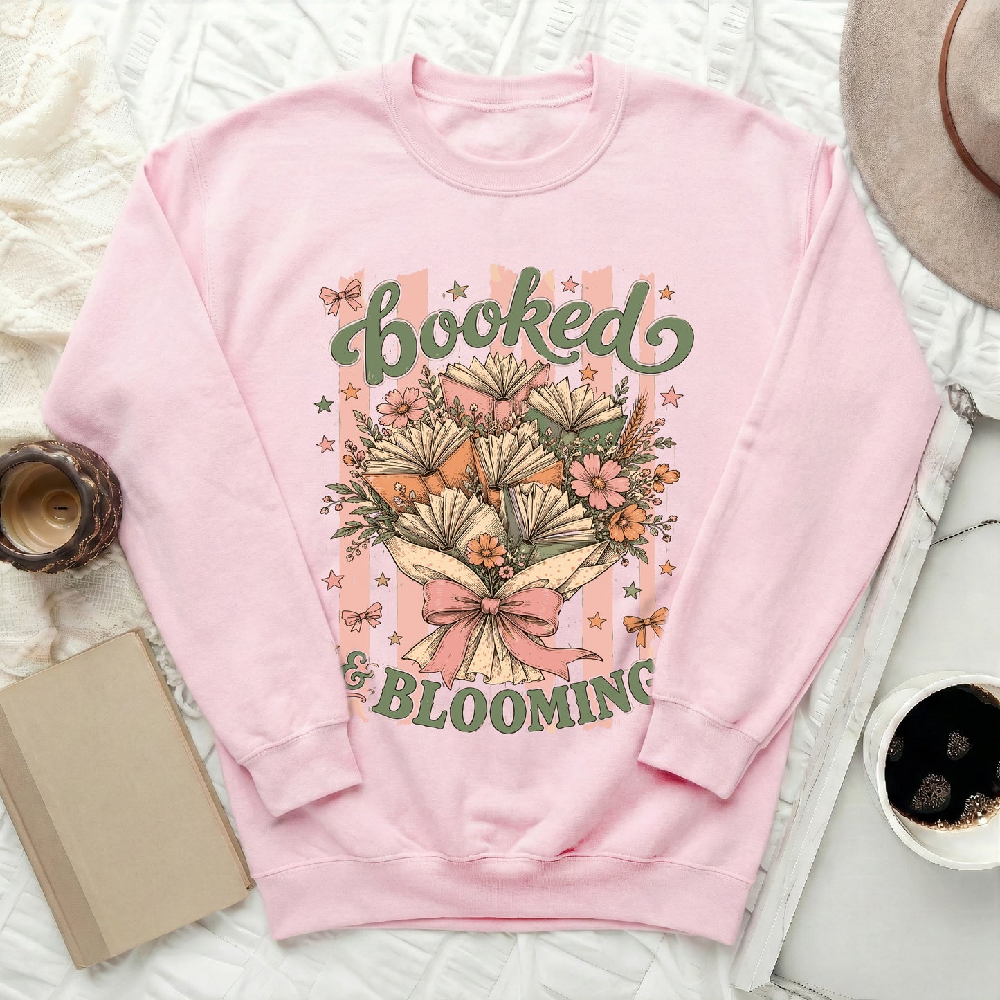 Pink sweatshirt with "Booked & Blooming" text and a bouquet of books and flowers.