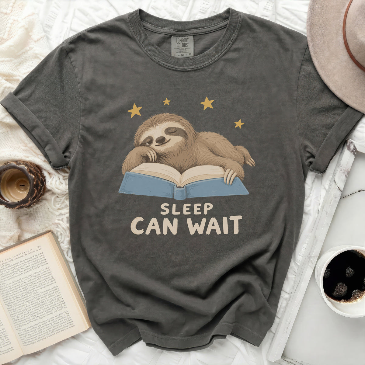 Sloth sleeping on a book with text "SLEEP CAN WAIT" and stars.
