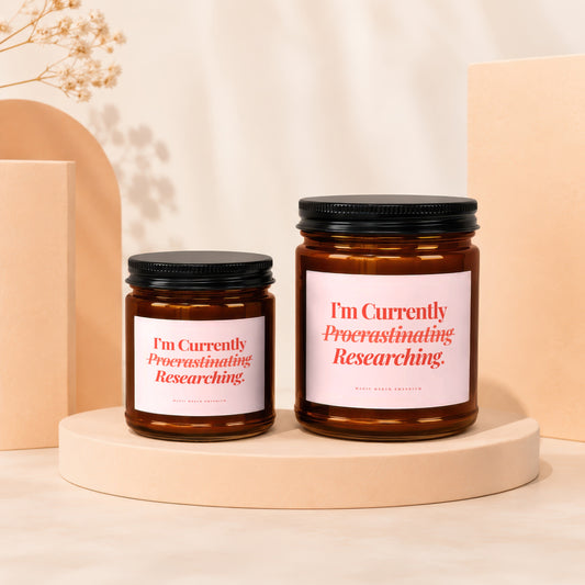 Two amber glass candles with black lids, labels read "I'm Currently Procrastinating Researching."